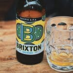 Butelka piwa Brixton Brewery Pacific APA i szklanka na drewnianym stole